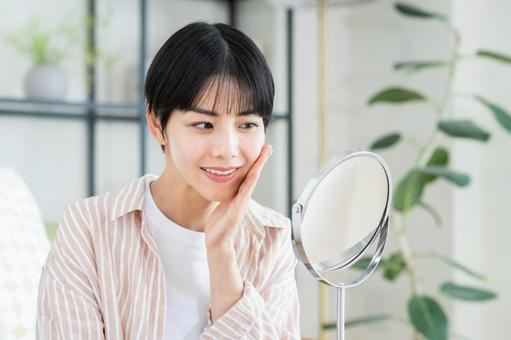 肝斑治療でよくある質問:顔に手を当て鏡をみる女性の写真