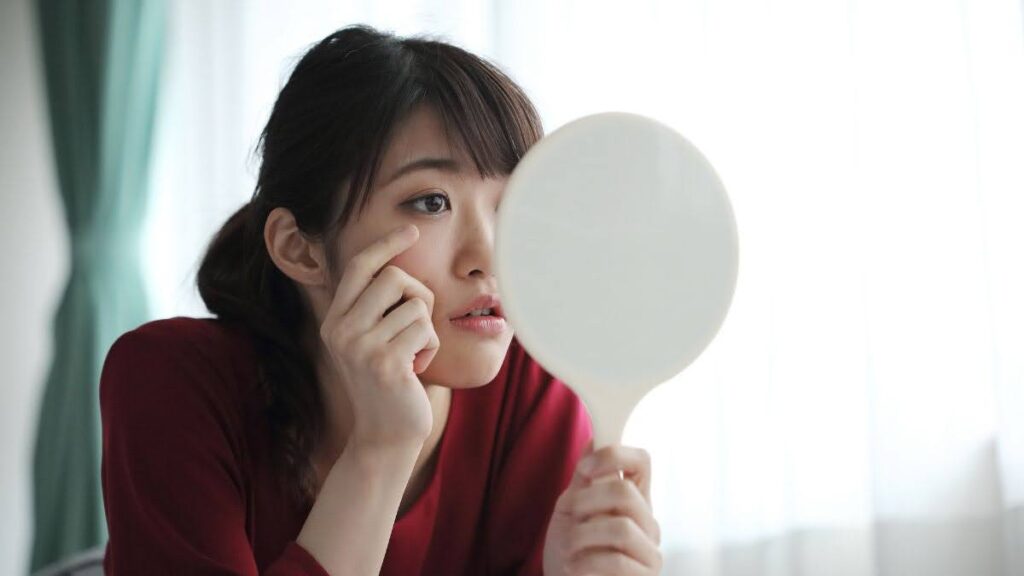 シミと肝斑の見分け方:女性が手鏡を持って顔を見ている写真